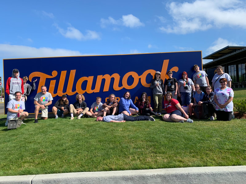 a group of youth and adults gathered in front of the Tillamook sign