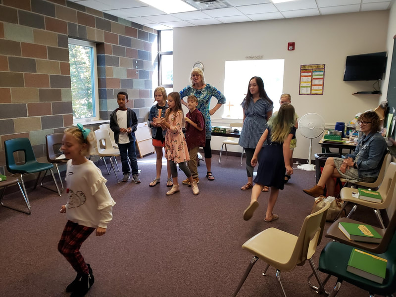 a group of children and adults dancing in a room