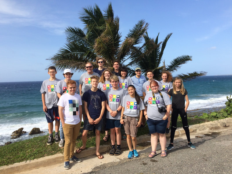 a group of youths gathered in front of palm trees on a seaside
