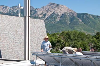 A photo of people on the roof of the church, installing solar panels.